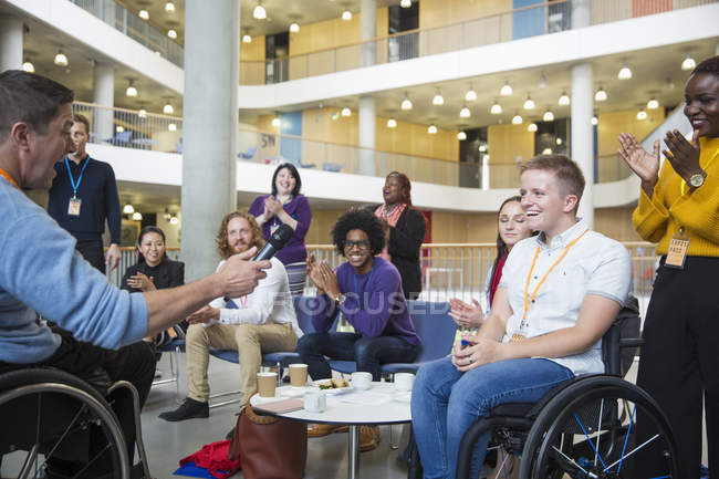 Colleagues clapping for speaker in wheelchair at conference — Stock Photo