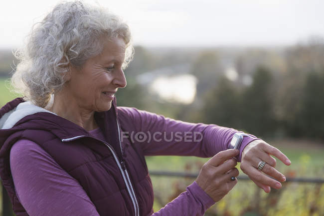 Donna anziana attiva che esercita, utilizzando fitness tracker smart watch — Foto stock