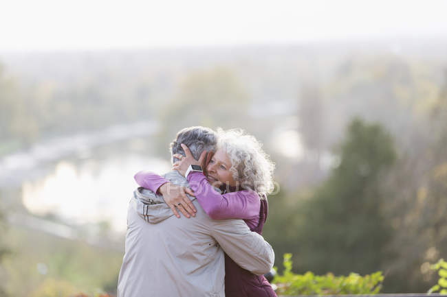 Affectionate active senior couple hugging in nature — Stock Photo