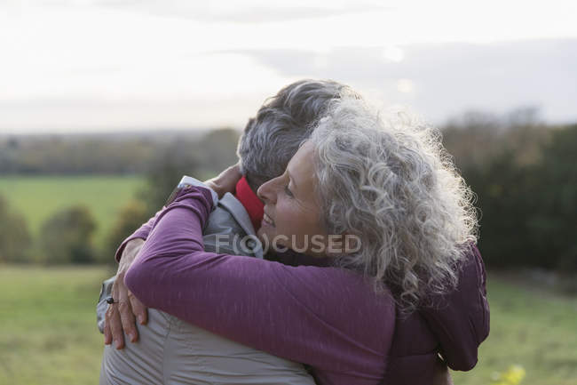Cariñosa pareja de ancianos abrazándose en el campo - foto de stock