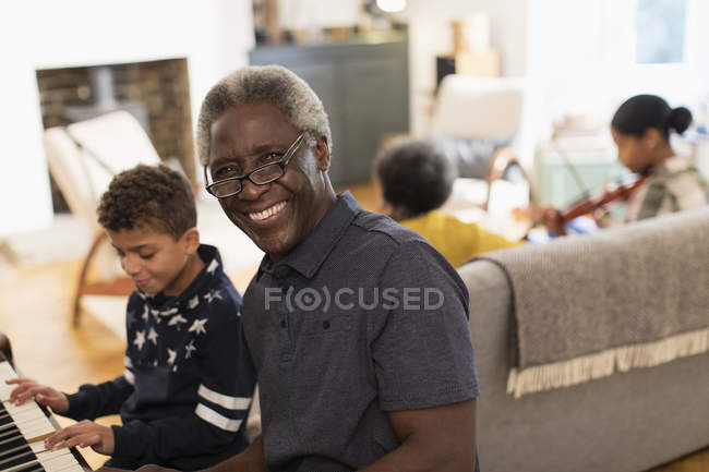 Retrato abuelo feliz tocando el piano con el nieto - foto de stock