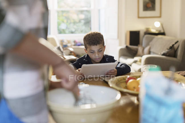 Цікавий хлопчик використовує цифровий планшет на кухні — стокове фото