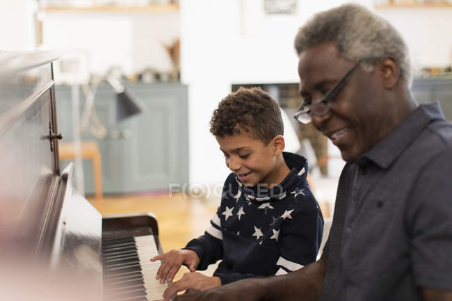 Дедушка и внук играют дома на пианино. — стоковое фото