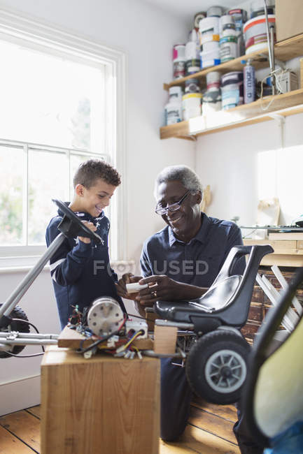 Grandfather and grandson assembling go-cart in garage — Stock Photo