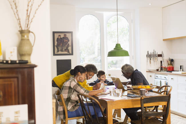 Бабусі і дідусі допомагають онукам з домашнім завданням за обіднім столом — стокове фото