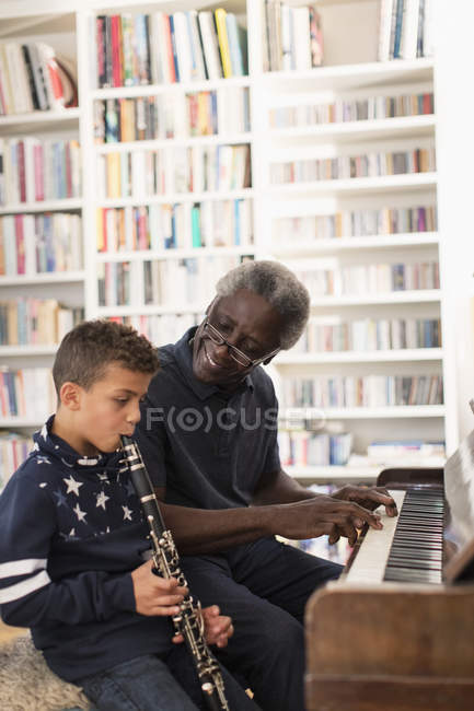 Дедушка и внук играют на пианино и кларнете — стоковое фото