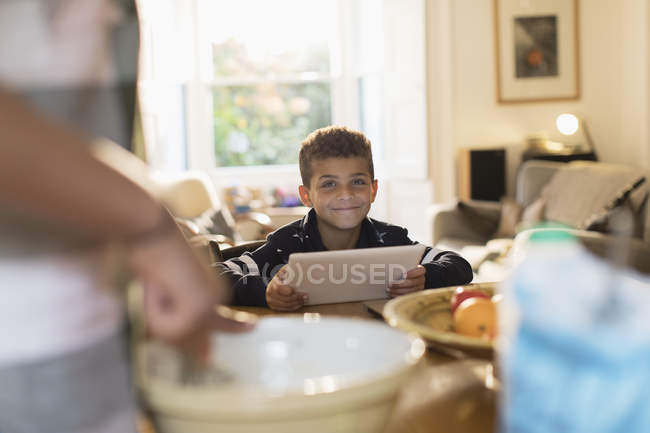 Портрет усміхненого хлопчика, який використовує цифровий планшет на кухні — стокове фото