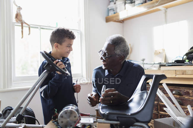 Дедушка и внук собирают повозку в гараже — стоковое фото