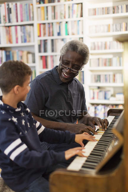 Abuelo y nieto tocando el piano en casa - foto de stock