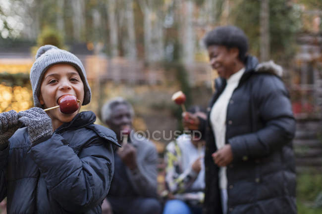 Портрет нетерпеливый мальчик ест конфетное яблоко на заднем дворе — стоковое фото