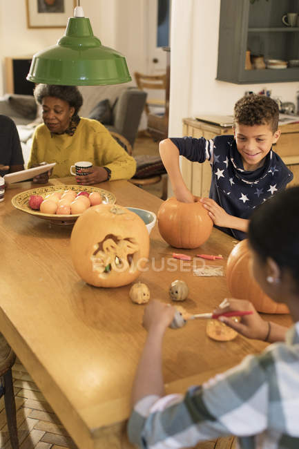 Familie schnitzt Halloween-Kürbisse am Esstisch — Stockfoto