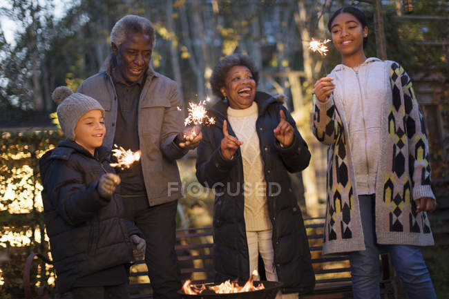 Grandparents and grandchildren playing with firework sparklers — Stock Photo