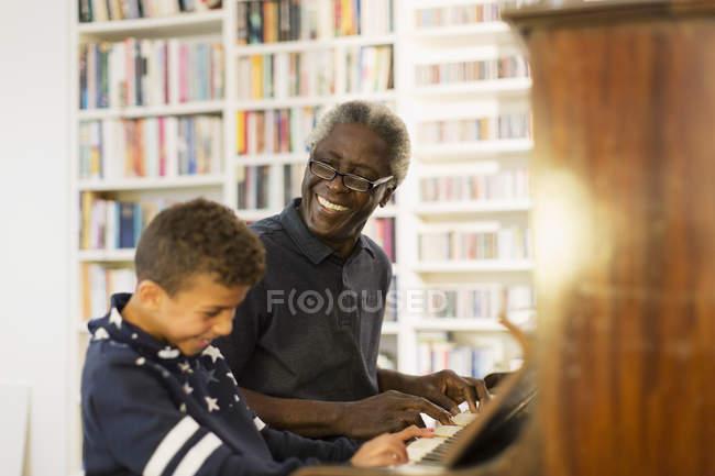 Счастливый дедушка и внук играют на пианино — стоковое фото