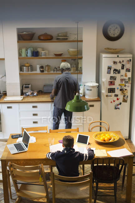 Дедушка и внук готовят и делают домашнее задание на кухне — стоковое фото