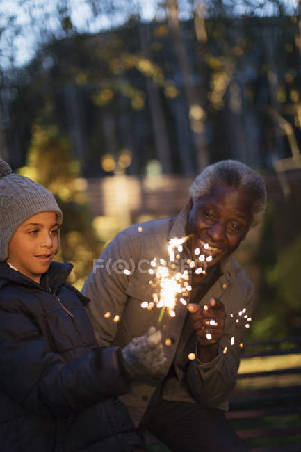 Grandfather and grandson playing with firework sparklers — Stock Photo