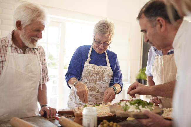Active senior friends making pizza in cooking class — Stock Photo