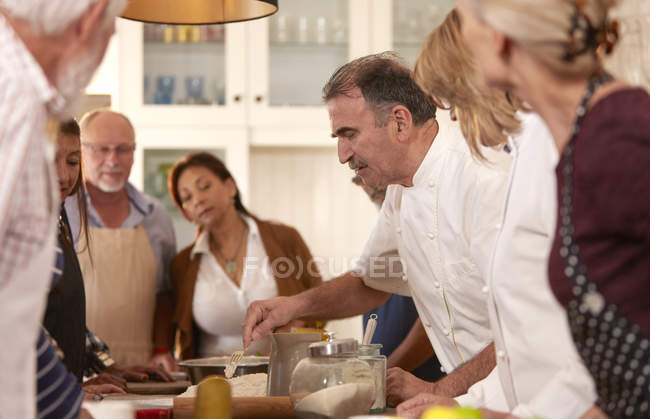 Chef explaining to active senior friends in cooking class — Stock Photo