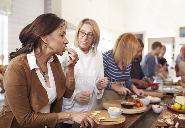 Senior woman and chef tasting cheese in pizza cooking class — Stock Photo