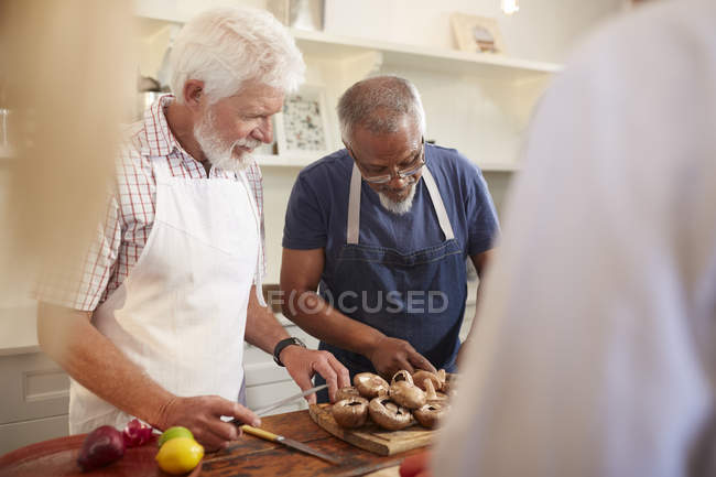 Senior hommes amis coupe champignons en cours de cuisine — Photo de stock