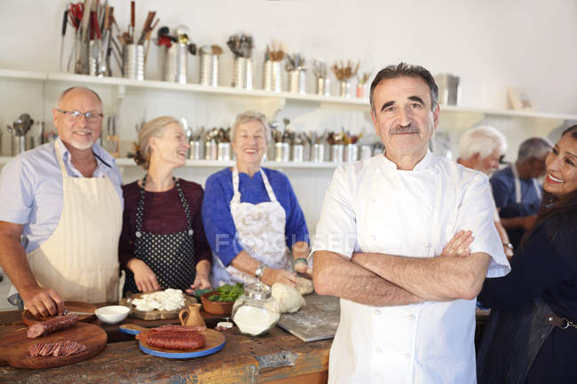 Portrait confident chef with senior students in cooking class kitchen — Stock Photo
