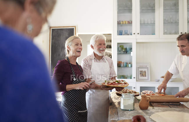 Senior couple making pizza in cooking class — Stock Photo