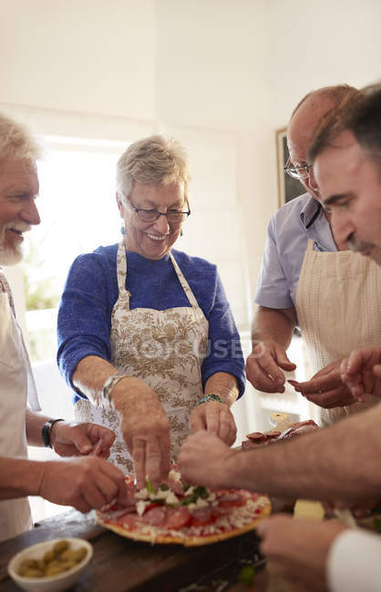 Старшие друзья делают пиццу на уроке кулинарии — стоковое фото