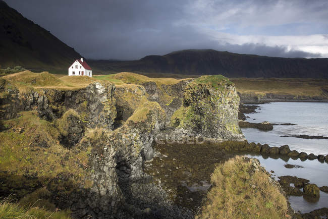 Удаленный дом на скале, Арнарстапи, Снайфельснес, Исландия — стоковое фото