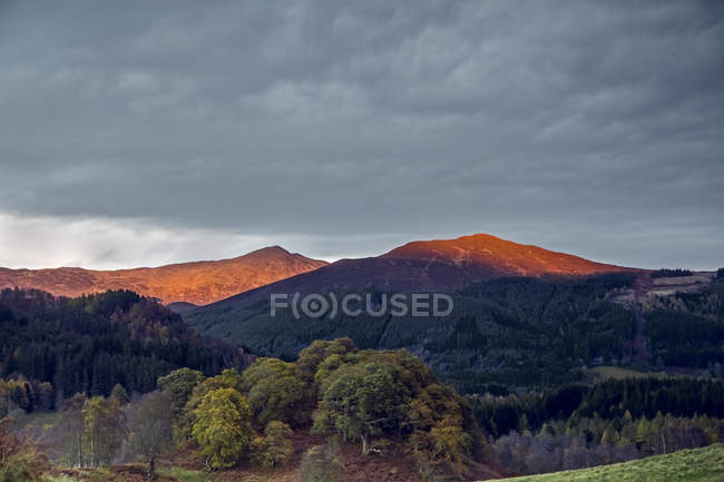 Luz solar iluminando tranquilas cimas de montañas, Escocia - foto de stock