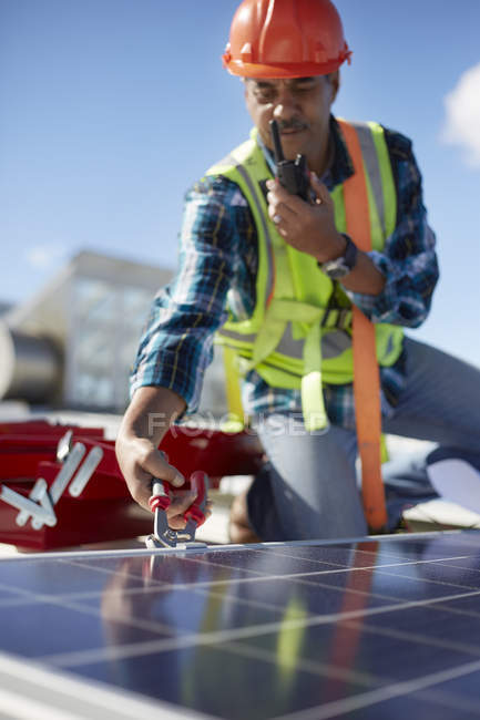 Ingeniero masculino con walkie-talkie reparando panel solar en planta de energía - foto de stock