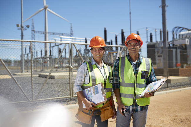 Ingenieros sonrientes y confiados con portapapeles en la central eléctrica - foto de stock
