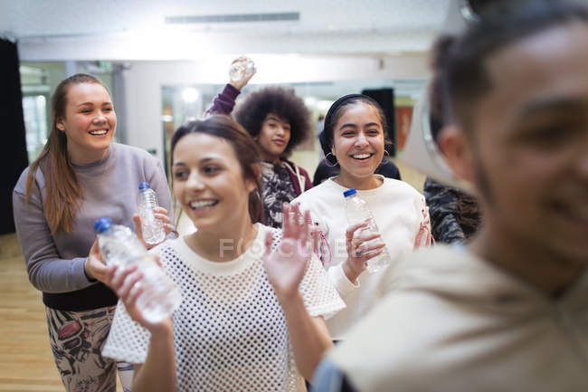Lächelnde, begeisterte Teenager-Mädchen, die Wasser trinken und im Tanzkurs im Studio jubeln — Stockfoto