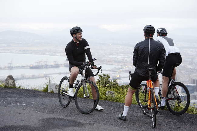 Male cyclist friends taking a break at overlook — Stock Photo
