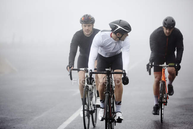 Dedicato ciclisti maschi in bicicletta su strada piovosa — Foto stock