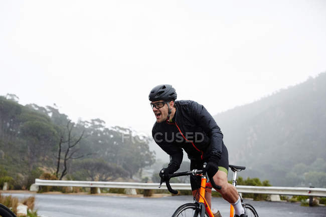Решительный мужчина-велосипедист, двигающийся в гору — стоковое фото
