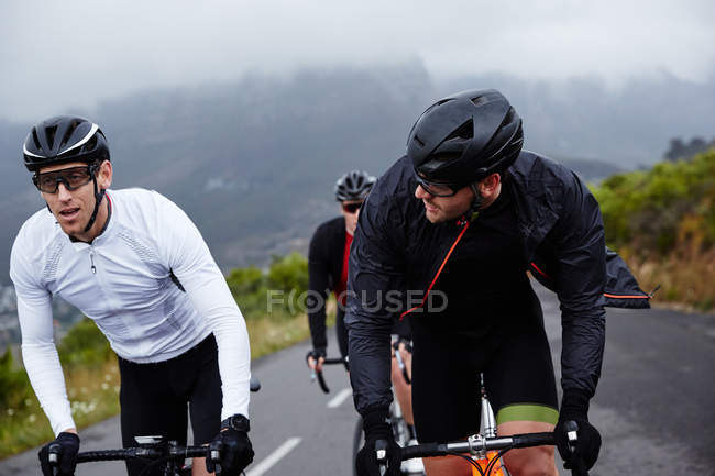 Male cyclist friends cycling on road — Stock Photo