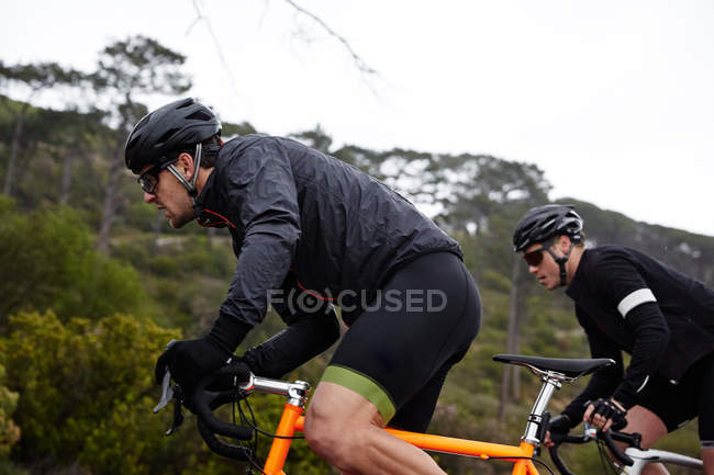 Ciclista masculino enfocado y determinado en bicicleta cuesta arriba - foto de stock
