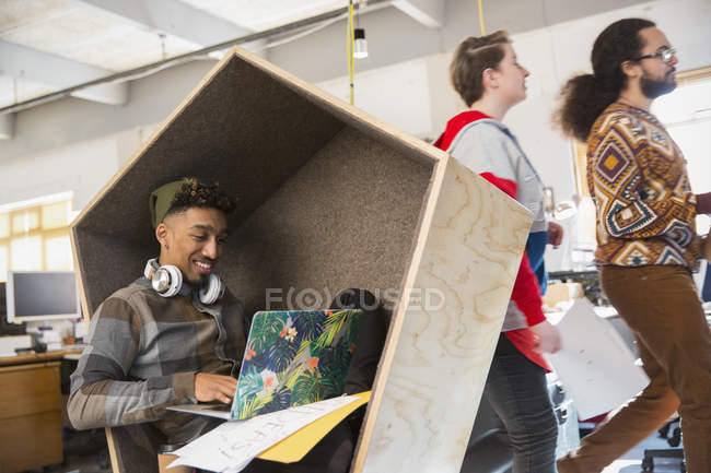 Creative businessman working at laptop in cubby — Stock Photo