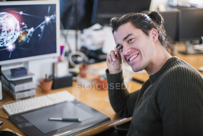Retrato sonriente, confiado diseñador gráfico masculino trabajando en el escritorio - foto de stock