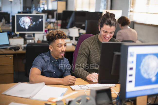 Creative businessmen working at computer in open plan office — Stock Photo
