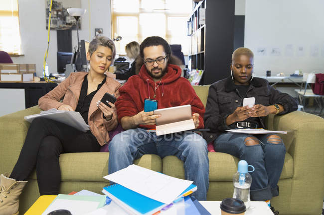 Творческие бизнесмены используют смартфоны, встречаются в обычном офисе — стоковое фото