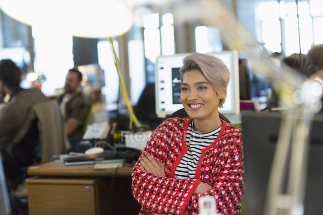 Mujer de negocios creativa sonriente y confiada que trabaja en la oficina - foto de stock