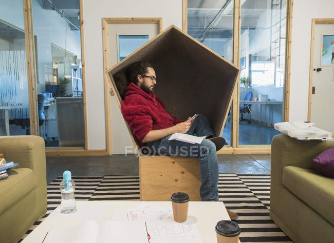 Creative businessman using smart phone in office cubby — Stock Photo