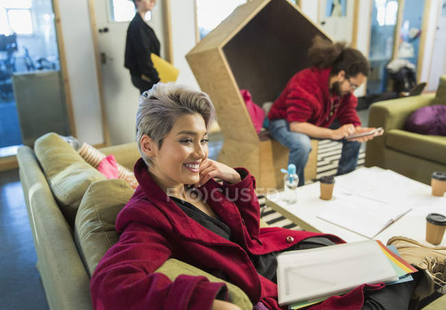 Femme d'affaires créative souriante avec de la paperasse dans un bureau décontracté — Photo de stock