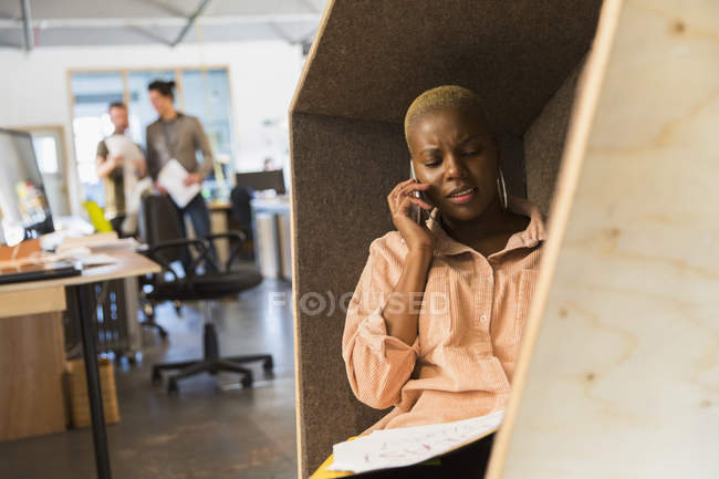 Creative businesswoman talking on smart phone in office cubby — Stock Photo