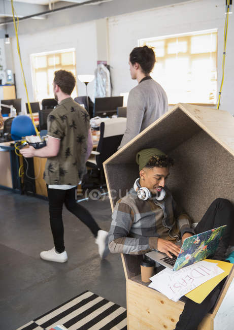Креативний бізнесмен з навушниками, використовуючи ноутбук в офісі кубик — стокове фото