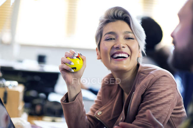 Risas empresaria creativa apretando la bola de estrés en la oficina - foto de stock
