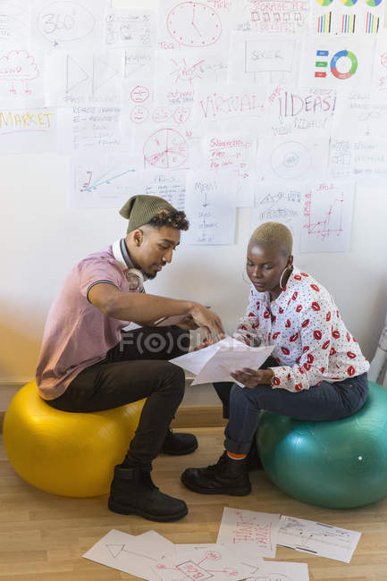 Creative business people on fitness balls meeting, brainstorming and discussing paperwork in office — Stock Photo