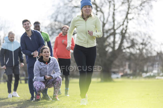 Team cheering woman running in park — Stock Photo