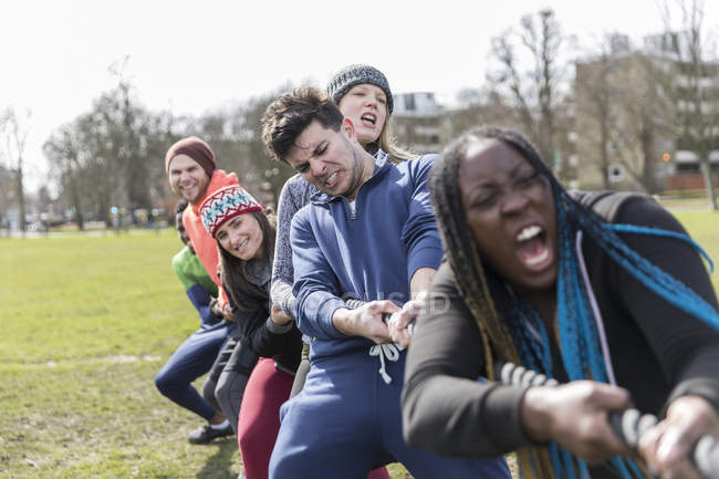 Determined team pulling rope in tug-of-war in park — Stock Photo