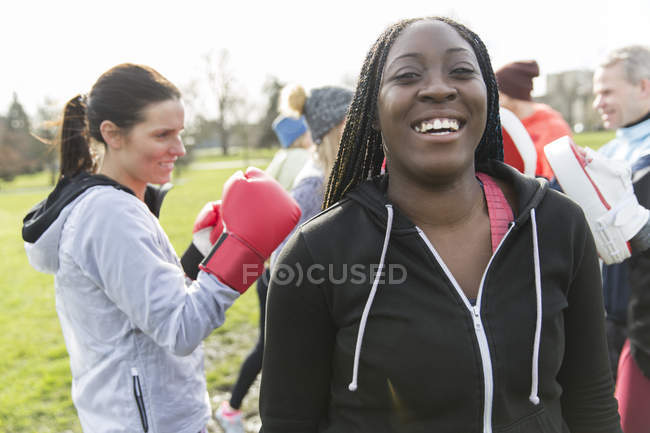Портрет улыбается, уверенная женщина боксирует в парке с друзьями — стоковое фото